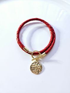 18kt gold filled Dragonfly wrap bracelet. This beautiful bracelet is made with a 1/2-inch 18kt gold Dragonfly medallion on a red braided leather cord that wraps around your wrist twice and has a gold toggle clasp.  This bracelet fits a 7-inch wrist but if you would like a different size please place your size request in the personalization box at checkout. the size shown fits most 6.5 to 7-inch wrists. Adjustable Gold Leather Bracelet With Brass Hardware, Adjustable Gold Leather Bracelet With Gold-tone Hardware, Luxury Leather Bracelet With Gold-tone Hardware For Formal Occasions, Luxury Leather Bracelet With Gold-tone Hardware, Elegant Gold-tone Brass Charm Bracelet, Toggle Clasp, Braided Leather, Leather Wraps, Leather Cord