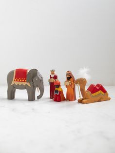 three small figurines in the shape of elephants and camels on a white surface