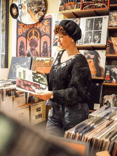 a woman is looking at records in a record store while holding one of her hands