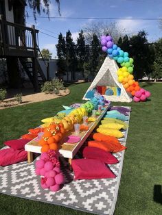 a long table with balloons and decorations on it in the middle of a grassy area