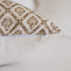 a close up of a pillow on a bed with white sheets and pillows in the background