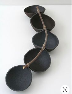 four black bowls are stacked on top of each other and one has a twig sticking out of it