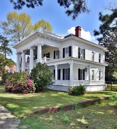 a large white house sitting on top of a lush green field