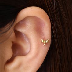 a woman's ear with a tiny gold flower on it