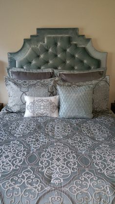 a bed with blue and white comforter, pillows and headboard