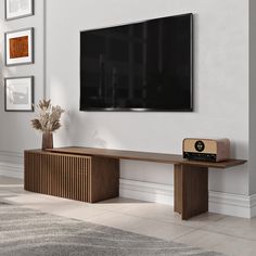 a flat screen tv mounted to the side of a wall next to a wooden shelf