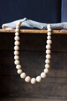 a wooden beaded necklace hanging from a wood shelf next to a piece of driftwood