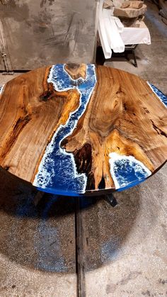 a table made out of wood with blue paint on the top and white waves painted on it