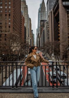 a woman standing on the side of a road in front of tall buildings