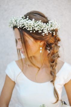 a woman wearing a white dress and a flower crown on her head with braids