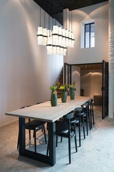 a dining room table with chairs and vases on the table in front of it