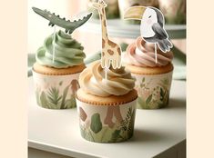 three cupcakes with frosting decorated like animals and giraffes on them