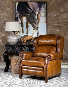 a brown leather chair sitting in front of a painting