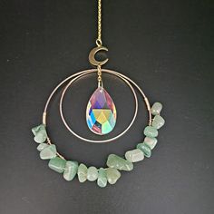 a necklace with stones and a crescent hanging from it's side on a black surface