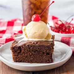 a piece of chocolate cake with ice cream on top and a cherry in the background