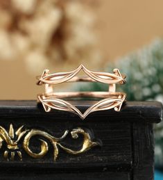 a gold ring sitting on top of a wooden table next to a vase with flowers