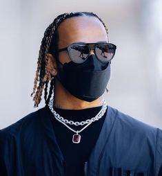 a man with dreadlocks wearing a black face mask and chain around his neck