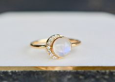 "Lovely genuine blue moonstone is set in 14k gold. Perfect as an engagement or for those who like to make a statement. Moonstones have long been revered across cultures and centuries for it's connection with the moon and hence it's positive effects on women. Combined with a girl's best friend - diamonds - this makes almost a perfect gemstone combination for a woman you love. The moonstone cabs are super sparkly and a lovely opaque color with blue tones and an excellent cut that shows off the bri White Moonstone Celestial Ring In 14k Gold, White Celestial Moonstone Ring In 14k Gold, White Moonstone Ring With Moon Phase For Anniversary, Moon Shaped Celestial Moonstone Ring For Anniversary, Elegant White Moon-shaped Opal Ring, Elegant White Moon Shaped Opal Ring, White Moonstone Ring With Moon Phase For Weddings, Moon-shaped Moonstone Ring For Wedding, Elegant Opal Moon Ring For Anniversary