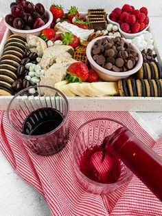 a platter filled with chocolate, fruit and crackers next to a glass of red wine