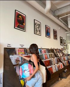 a woman looking at records on display in a record store with posters above the shelves