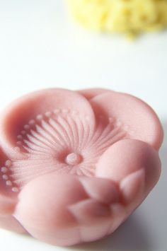 a close up of a pink flower shaped object on a white surface with other items in the background