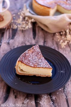 a slice of cheesecake on a plate with powdered sugar and coffee in the background