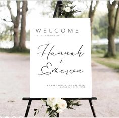 a welcome sign with flowers and greenery is displayed on an easel in front of a path