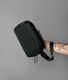 a person with tattoos holding a black bag