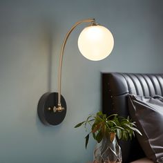 a lamp that is on the wall next to a potted plant in a vase