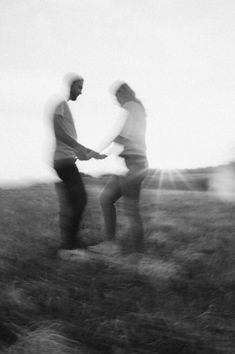 black and white photograph of two men standing in a field with one holding the other's hand