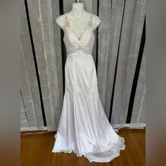 a white wedding dress is on display in front of a striped wall and wooden floor