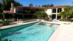 a large house with a swimming pool in front of it and trees around the pool