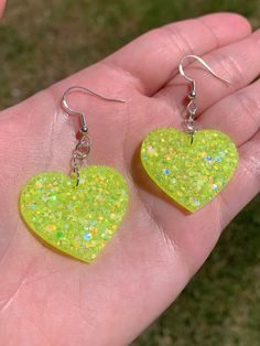 "Each pair of resin earrings are handmade to order, therefore no two pairs are identical! However, I try to get as close as possible :) Made with nickel free, hypoallergenic, sterling silver fish hooks.  Heart width is approximately 1.25\", and is made with epoxy resin and neon yellow holographic and iridescent glitter! 💛 UV / blacklight reactive! Perfect for concerts or raves ✨ Thanks for visiting my shop!" Green Heart Shaped Earrings For Parties, Resin Heart Earrings For Gifts, Cute Green Heart Earrings For Gift, Handmade Heart-shaped Resin Earrings, Heart-shaped Resin Earrings For Party, Yellow Heart Earrings For Gift, Yellow Heart-shaped Earrings For Gift, Trendy Green Heart Earrings For Gift, Neon Earrings