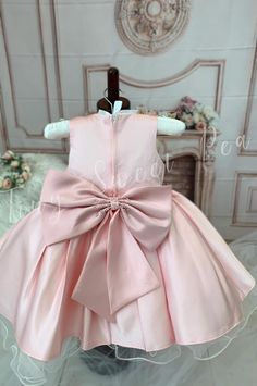 For a vision of chic elegance, look no further than our Glamorous Satin Dress for Little Girls. Available in either a regal white or stunning pink color, this high-quality, one-of-a-kind satin dress is perfect for any formal event or special occasion. The silhouette is classic, with a fitted bodice and a fluffy skirt that swirls delightfully at every twirl. Delicate patterns are beautifully embroidered on the bodice, giving an additional touch of sophistication. Each and every satin dress is met Elegant Sleeveless Dresses For Pageants, Pink Sleeveless Satin Gown, Sleeveless Pink Satin Gown, Elegant Spring Princess Dress For Baptism, Fitted Baptism Dress With Bow, Elegant Sleeveless Pageant Dress For Wedding, Elegant Sleeveless Wedding Pageant Dress, Sleeveless Party Dress With Pink Bow, Pink Party Dress With Bow