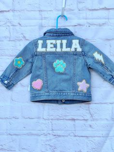 Our custom denim jackets for kids have the name of your choice sewn on the upper back panel of the jacket in chenille letter patches. These personalized jean jackets have additional chenille patches that are sewn on the back, sleeves and front. These name jackets for girls make the perfect customized gift for babies, toddlers and girls! DETAILS: -preppy style chenille patches with gold outline -customize to spell your child's name in 5 color options (pink, purple, white, turquoise, rainbow) -GAP Customizable Blue Denim Jacket, Customizable Denim Jacket For Fall, Customizable Blue Denim Jacket For Spring, Customizable Cute Cotton Outerwear, Cute Customizable Cotton Outerwear, Customizable Denim Outerwear For Fall, Customizable Long Sleeve Denim Jacket, Trendy Customizable Long Sleeve Denim Jacket, Customizable Denim Jacket