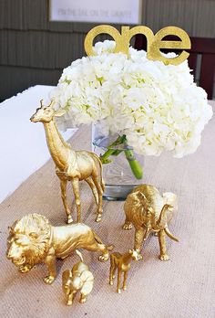 a vase filled with white flowers and gold figurines on top of a table