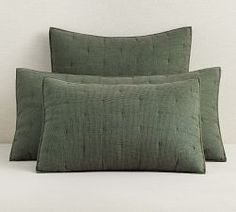 two green pillows sitting next to each other on a bed