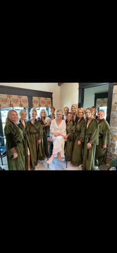 a group of people dressed in green robes posing for a photo with one woman sitting on a chair