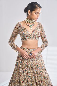 This antique gold net lehenga set has a dense sprinkling of all jewel tones of embroidery material - emerald, ruby, turquoise, gold, silver, pearl etc. It comes with a full sleeves blouse which has delicate tasselling at the sleeve hem and at the waist. The dupatta has four-sided border and dense sprinkling.From Seema Gujral’s Samode collectionDELIVERY TIMEPlease wait 8-12 weeks for your outfit to arrive.FABRIC DETAILSNetProfessional cleaning only. Bollywood Style Kundan Hand Embellished Sets, Bollywood Kundan Hand Embellished Sets, Bollywood Kundan Hand-embellished Sets, Wedding Lehenga Hand Embellished In Multicolor, Multicolor Sequined Sets For Reception, Multicolor Hand Embellished Bollywood Sets, Hand Embellished Multicolor Bollywood Sets, Glamorous Gold Hand Embellished Sharara, Glamorous Gold Hand-embellished Sharara