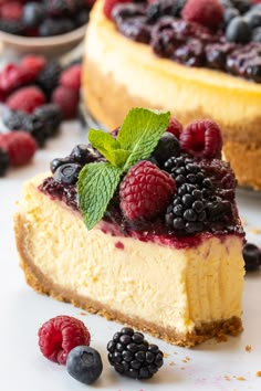 a cheesecake with berries on top is sitting on a cooling rack next to another piece of cake