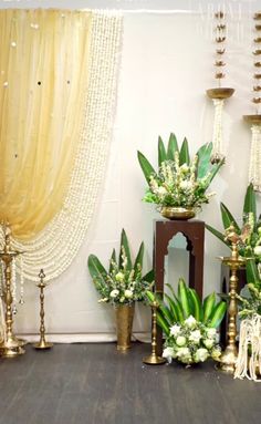 an arrangement of flowers and candles on display in front of a curtained window with drapes