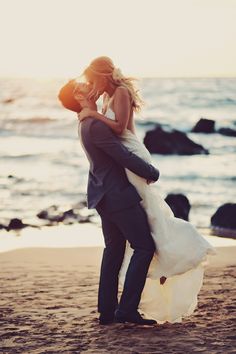 black and white photograph of bride and groom hugging on the beach with ocean in background