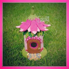 a pink flower is growing out of a birdhouse