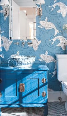 the bathroom is decorated in blue and white with gold fish on the wall behind it