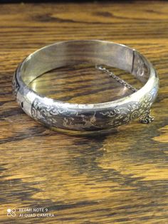 "Super Quality Niello Silver Siam Bangle. As the piece is marked Siam Sterling, it would indicate that it was made pre 1949. Nielloware jewellery were popular gifts from American soldiers taking \"R&R\" in Thailand to their girlfriends/wives back home from the 1930s to the 1970s. Most of it was completely handmade jewellery. The technique is as follows: The artisan would carve a particular character or pattern into the silver, leaving the figure raised by carving out the \"background\". He would then use the niello inlay to fill in the \"background\". After being baked in an open fire, the alloy would harden. It would then be sanded smooth and buffed. Finally, a silver artisan would add minute details by hand. Filigree was often used for additional ornamentation. Nielloware is classified a Classic Round Ceremonial Cuff Bracelet, Classic Round Cuff Bracelet For Ceremonial Occasions, Antique 17 Jewels Bracelet For Anniversary, Heirloom Bangle Bracelets For Anniversary, Heirloom Bangle Bracelet For Anniversary, Heirloom Anniversary Bangle Bracelet, Vintage Cuff Bracelet With 17 Jewels For Formal Occasions, Ornate Stamped Bracelets For Formal Occasions, Classic Etched Bangle Jewelry