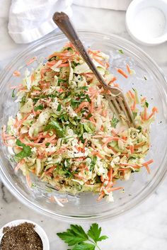 a glass bowl filled with coleslaw and carrots