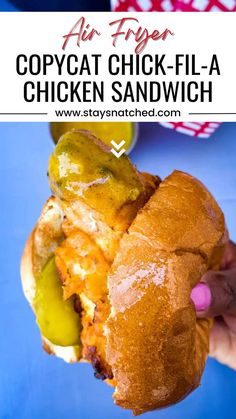 a person holding up a chicken sandwich with pickles and cheese on it in their hand