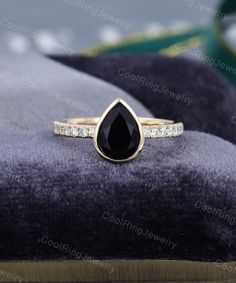 an engagement ring with a pear shaped black diamond in the center and diamonds around it