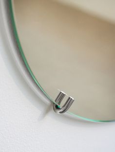 a close up of a mirror with a metal ring on it's end and a white wall in the background