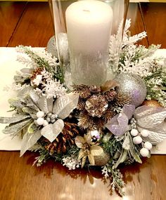 a candle is sitting on top of a table with christmas decorations and greenery around it